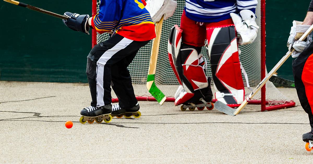 Zwei Personen spielen vor einem Tor Inline-Hockey in Schutzkleidung